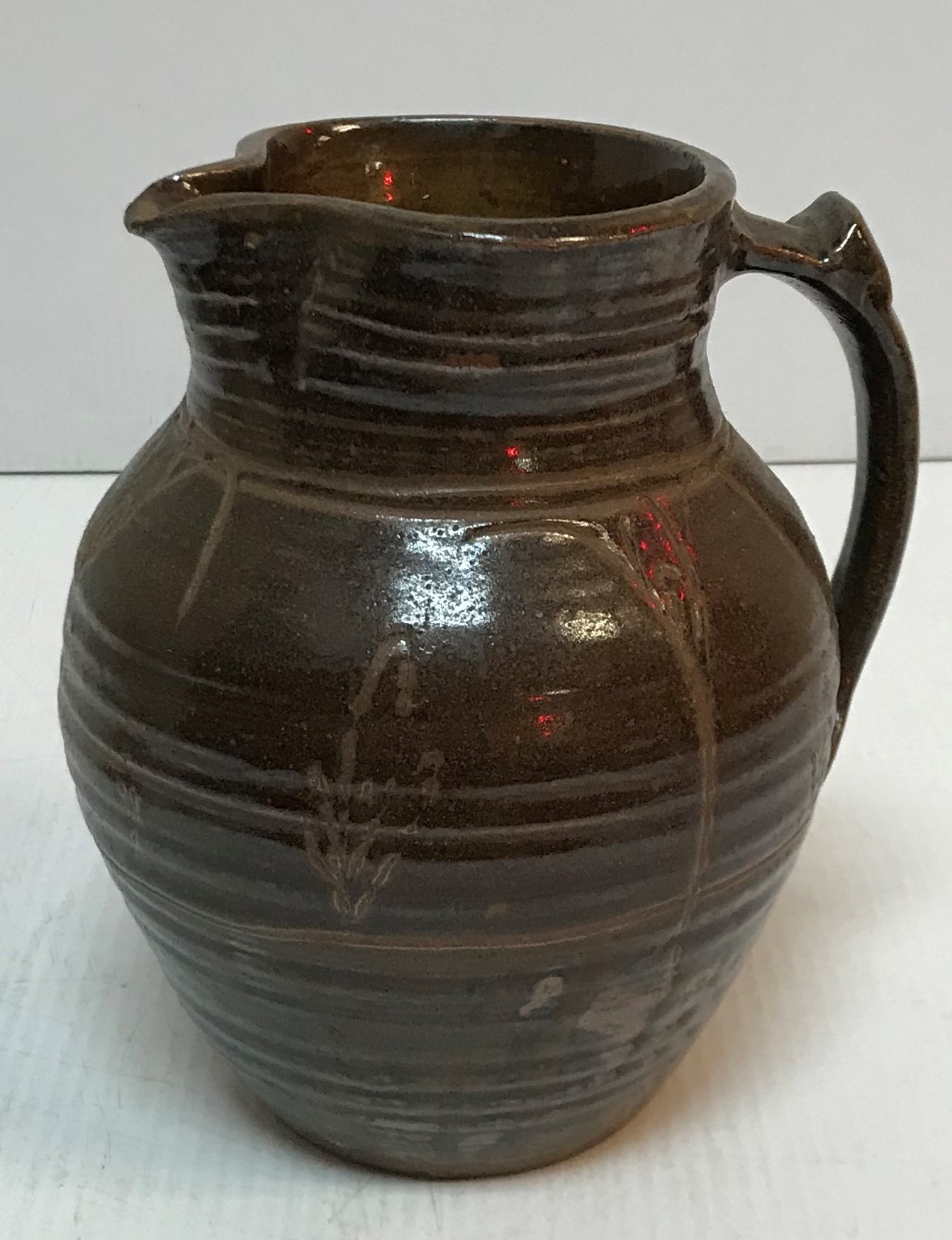 A Michael Cardew Wenfordbridge Pottery brown glazed ribbed jug with stylized floral spray