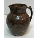 A Michael Cardew Wenfordbridge Pottery brown glazed ribbed jug with stylized floral spray