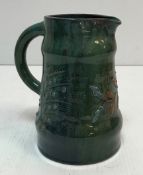 An Elton Pottery jug with relief work floral spray decoration on a deep green blue ground 19 cm