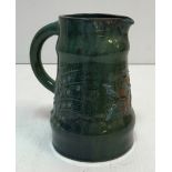 An Elton Pottery jug with relief work floral spray decoration on a deep green blue ground 19 cm