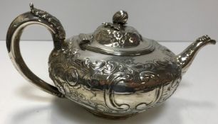 A Victorian embossed silver teapot of squat form with all-over floral and foliate decoration and