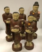 A carved and painted collection of five Tibetan figures of disciples or monks with food bowls in