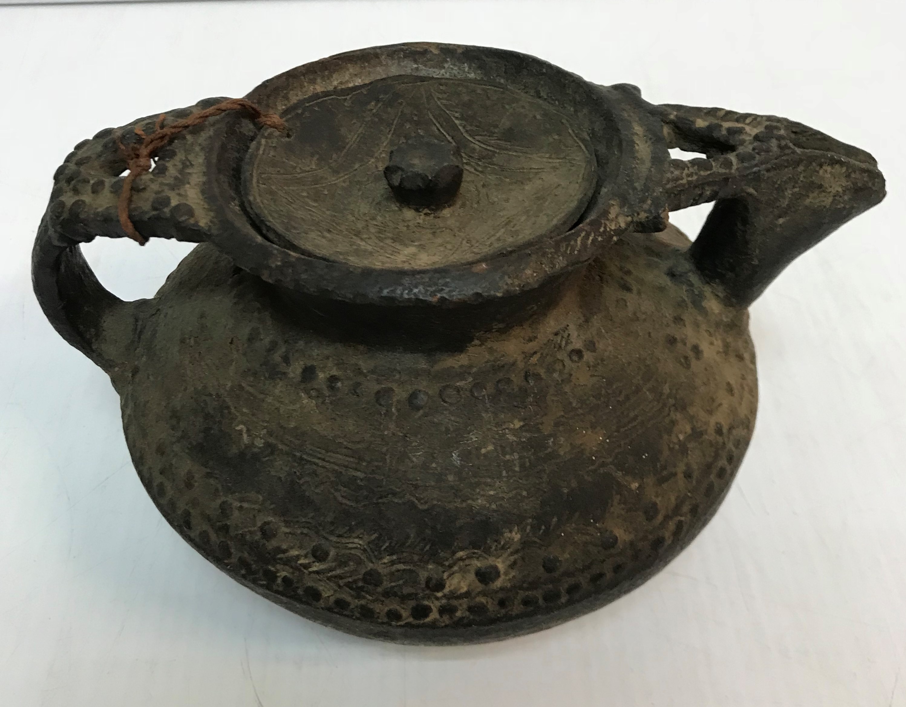 An African terracotta teapot of bellied form with roundel and incised decoration, 13.