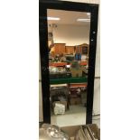 A modern black framed rectangular wall mirror,