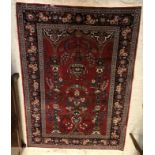 A Persian carpet, the central panel set with Mirhab design and vase of flowers on a red ground,
