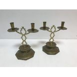 A pair of Arts & Crafts style brass twin branch candelabra, raised on octagonal stepped bases,