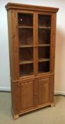 A modern pine cabinet with two glazed doors enclosing three shelves over two fielded panel doors