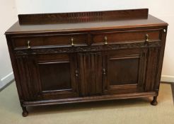 An early 20th Century oak dresser with shallow raised back over two drawers and two panelled