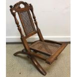 A Victorian child's folding caned campaign style chair with acanthus carved scrollwork top rail on