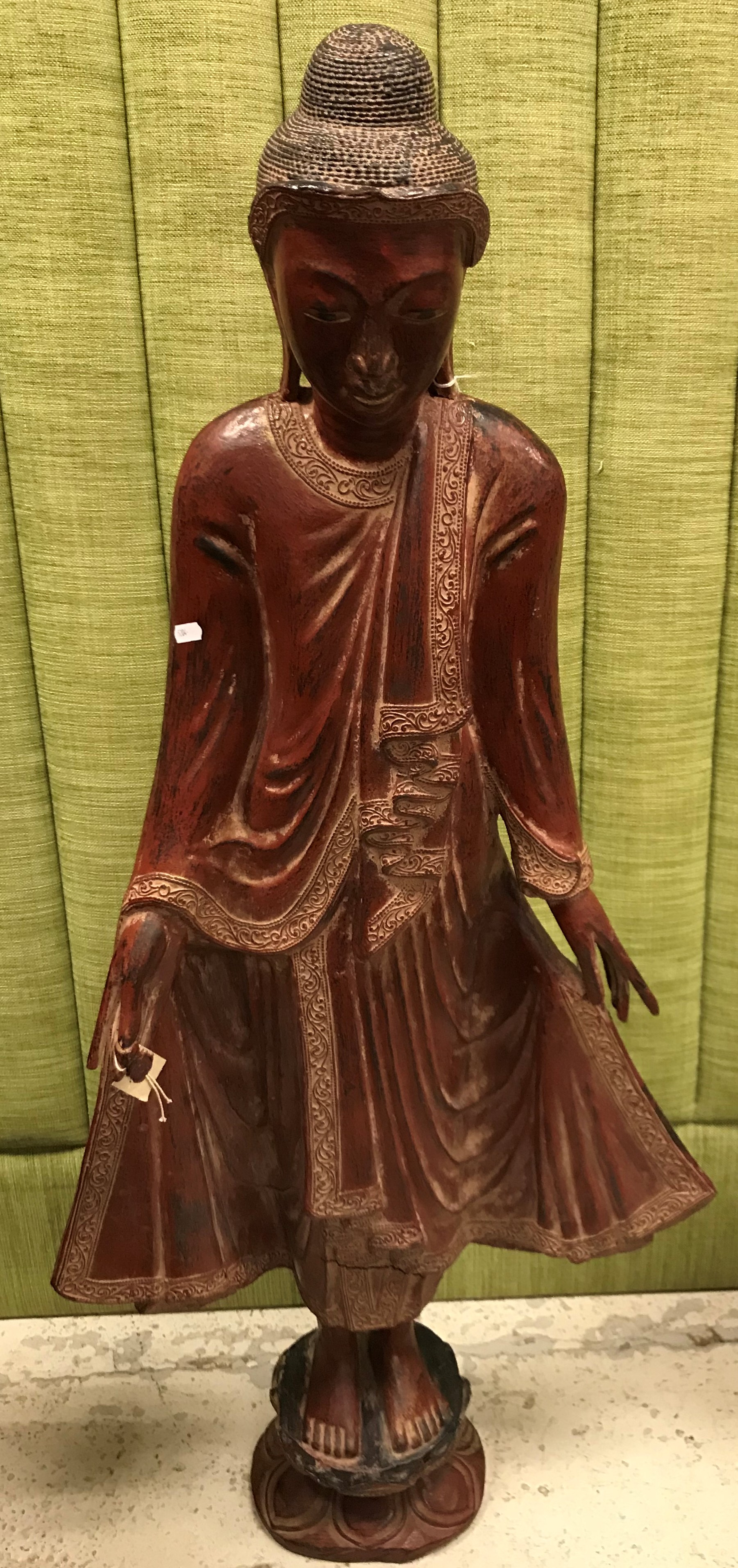 A Burmese red and gilt lacquered figure of a standing buddha on a lotus leaf decorated integral