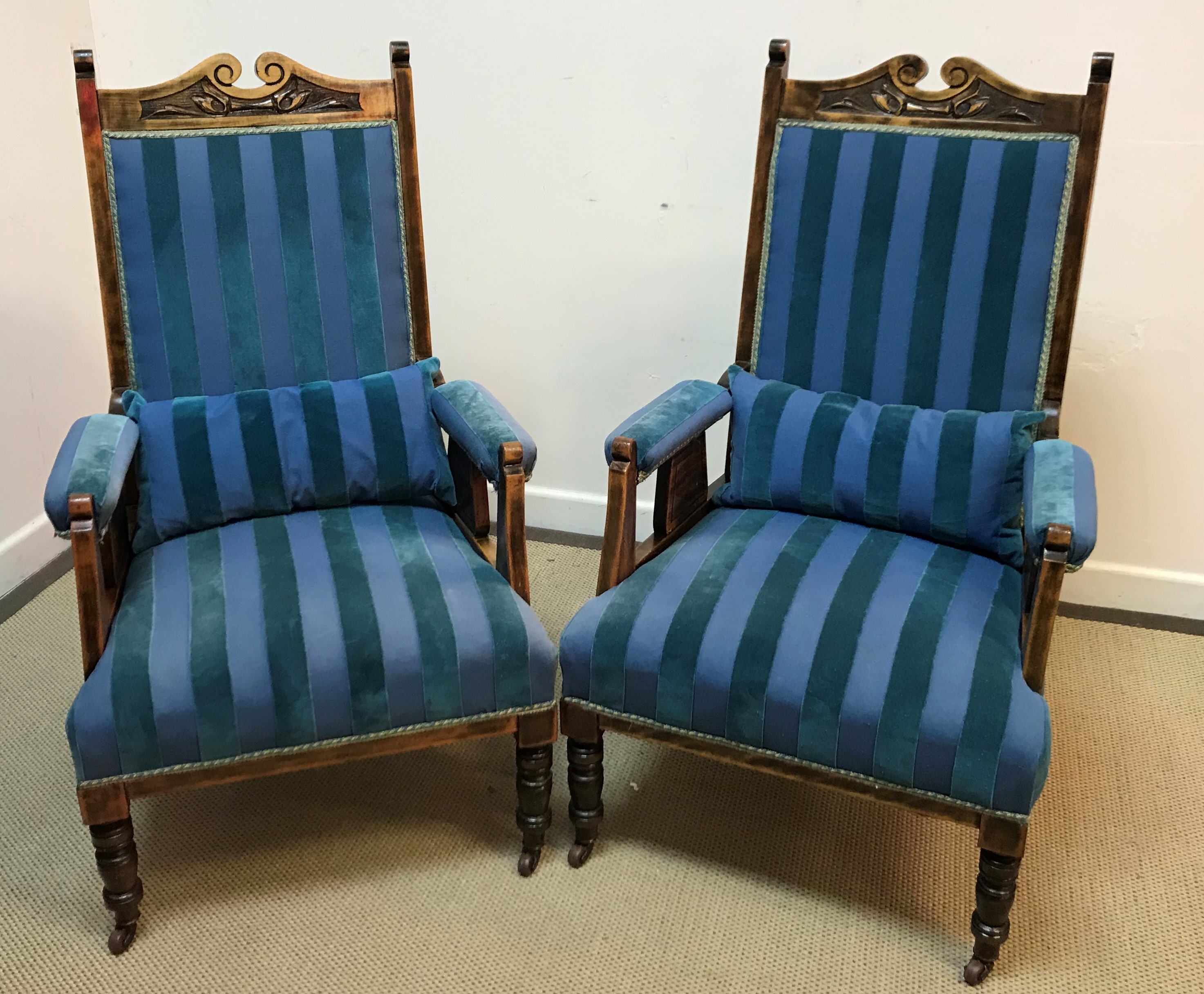 A pair of late Victorian stained beech salon armchairs with foliate carved top rail above