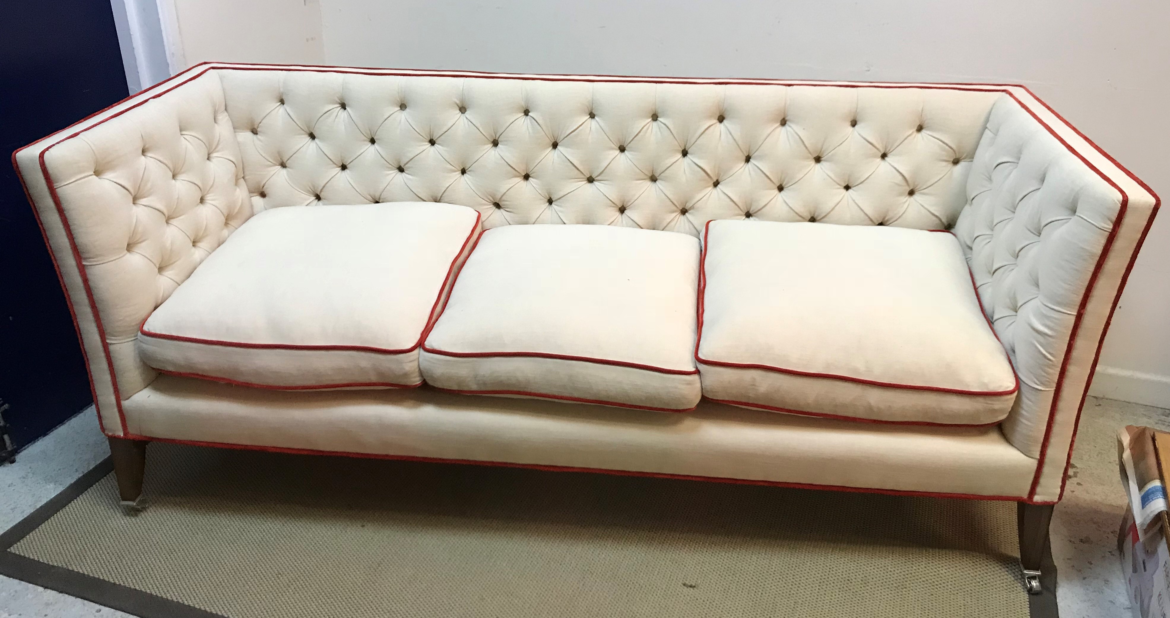 A Lawson Wood cream buttoned knowle style three seat sofa with scarlet velvet piping,