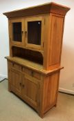 A modern teak dresser with two glazed doors over a recess on a base of three drawers over two