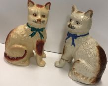 Two pottery cats, one wearing a green bow, the other blue, 20.