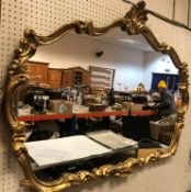 A 20th Century gilt framed wall mirror with scallop shell finial and C scrolling decoration 90 cm x