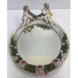 A Sitzendorf porcelain wall mirror of oval form decorated with cherubs and floral wreath and