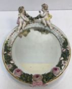 A Sitzendorf porcelain wall mirror of oval form decorated with cherubs and floral wreath and