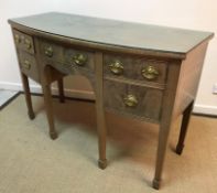 An Edwardian mahogany bow fronted sideboard with central drawer flanked by a pair of drawers and