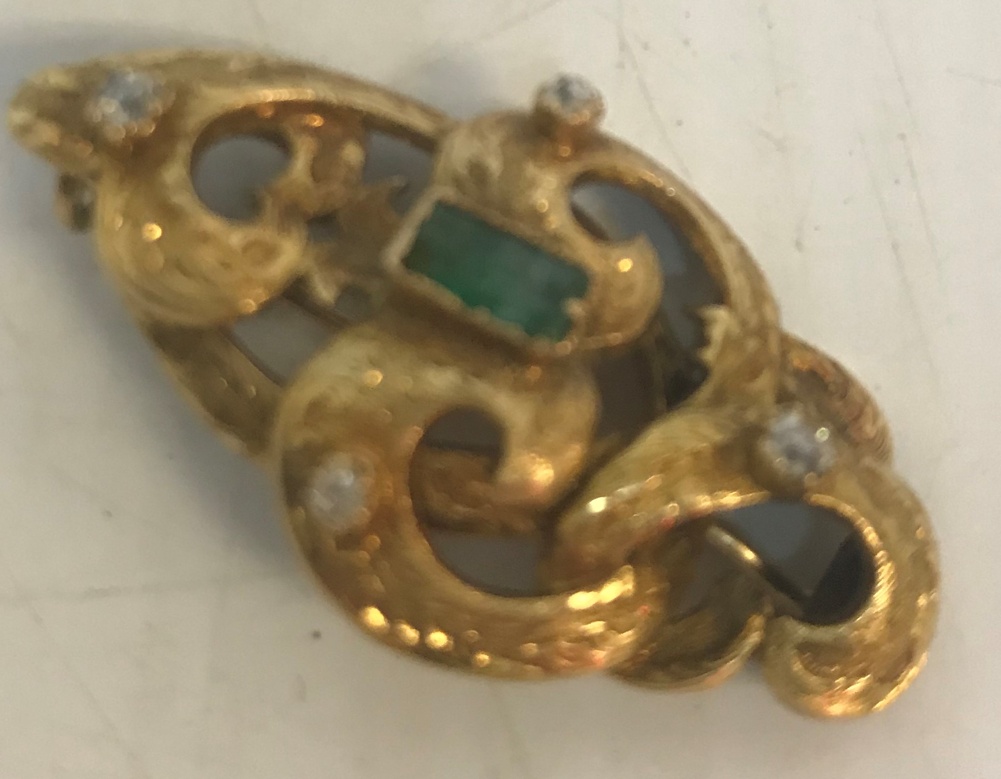 A 19th Century yellow metal brooch of entwined scrolling form set with four diamonds and a baguette