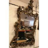 An 18th Century carved giltwood and gesso wall mirror in the Rococo manner with scrolling acanthus