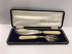 A cased George V fish serving set with silver blade and prongs and ivory handles (by Martin Hall &