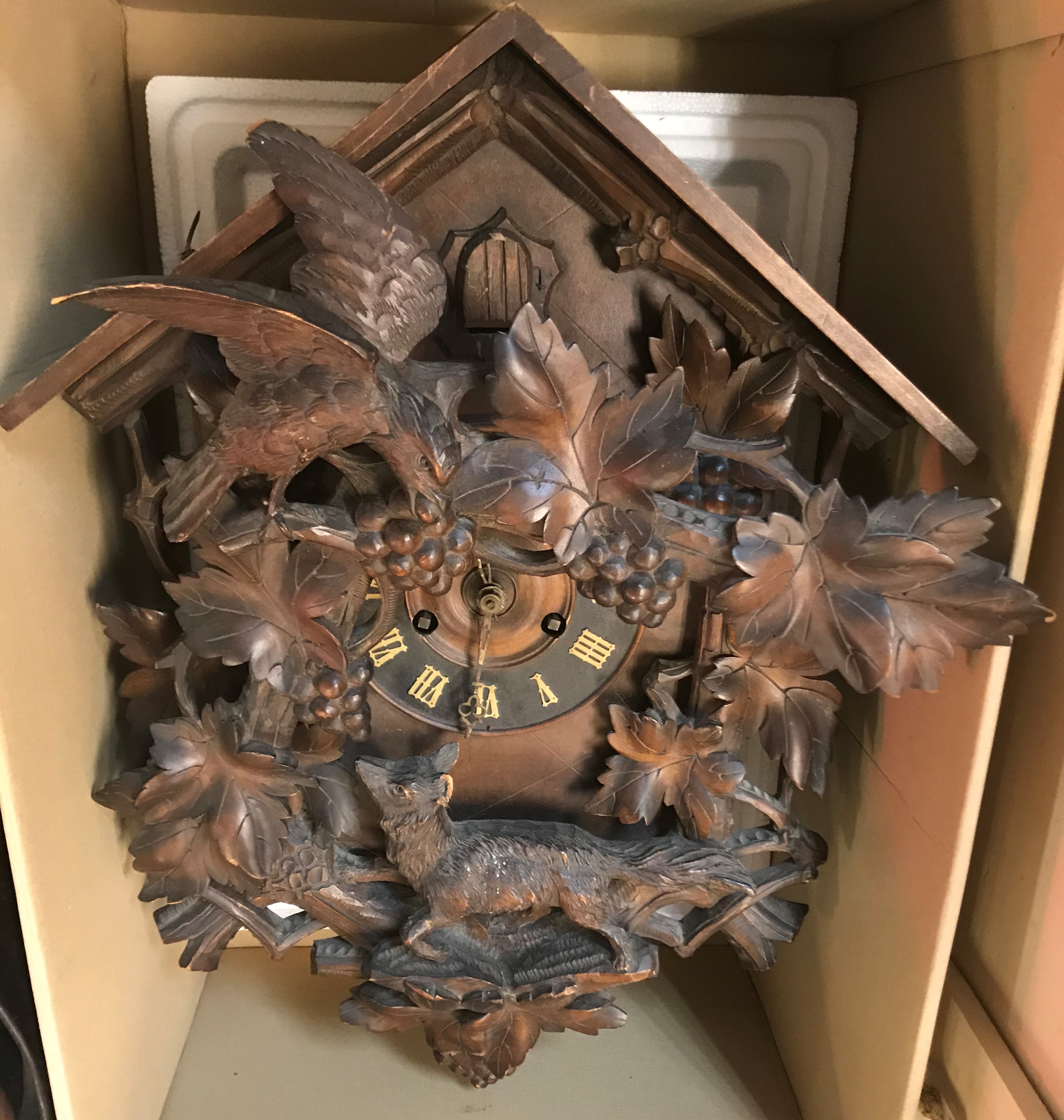 A 20th Century Black Forest style cuckoo clock with spreadeagle surmount over grape and vine carved