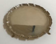 A George V silver salver with pie crust edge and raised on four hoof feet (London,