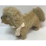 A wood wool filled pale gold plush mohair dog with tongue protruding and glass eyes and squeaker