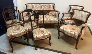 An Edwardian mahogany seven piece salon suite with carved floral and foliate decoration,