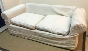 A modern upholstered scroll arm two seat sofa with cream / white loose covers,