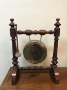 A late Victorian walnut framed brass gong with two leather covered wooden handled beaters,