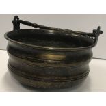 A 19th Century bronze bowl of circular ribbed form with swing handle,