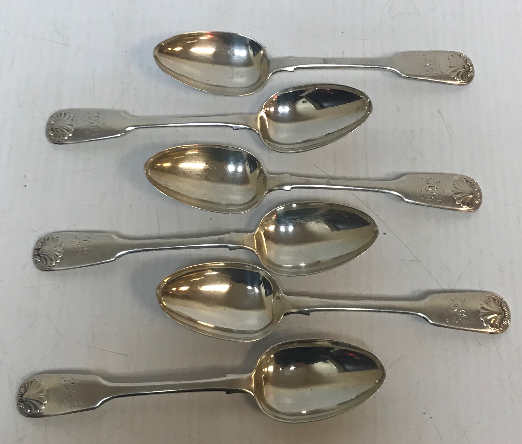 A set of six Victorian silver "Fiddle and shell" pattern dessert spoons with indistinct engraving