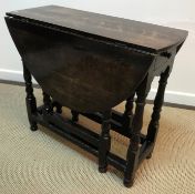 An oak oval gate-leg drop-leaf dining table in the 18th Century manner raised on baluster turned