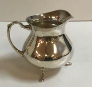 A modern silver milk jug of bellied form raised on three stylised hoof feet (Birmingham,
