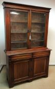 A Victorian mahogany bookcase cabinet with two glazed doors enclosing shelving over two drawers and