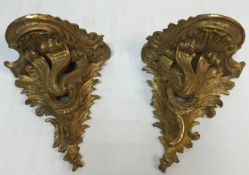 A pair of late 19th/early 20th Century carved giltwood and gesso wall brackets in the Rococo style
