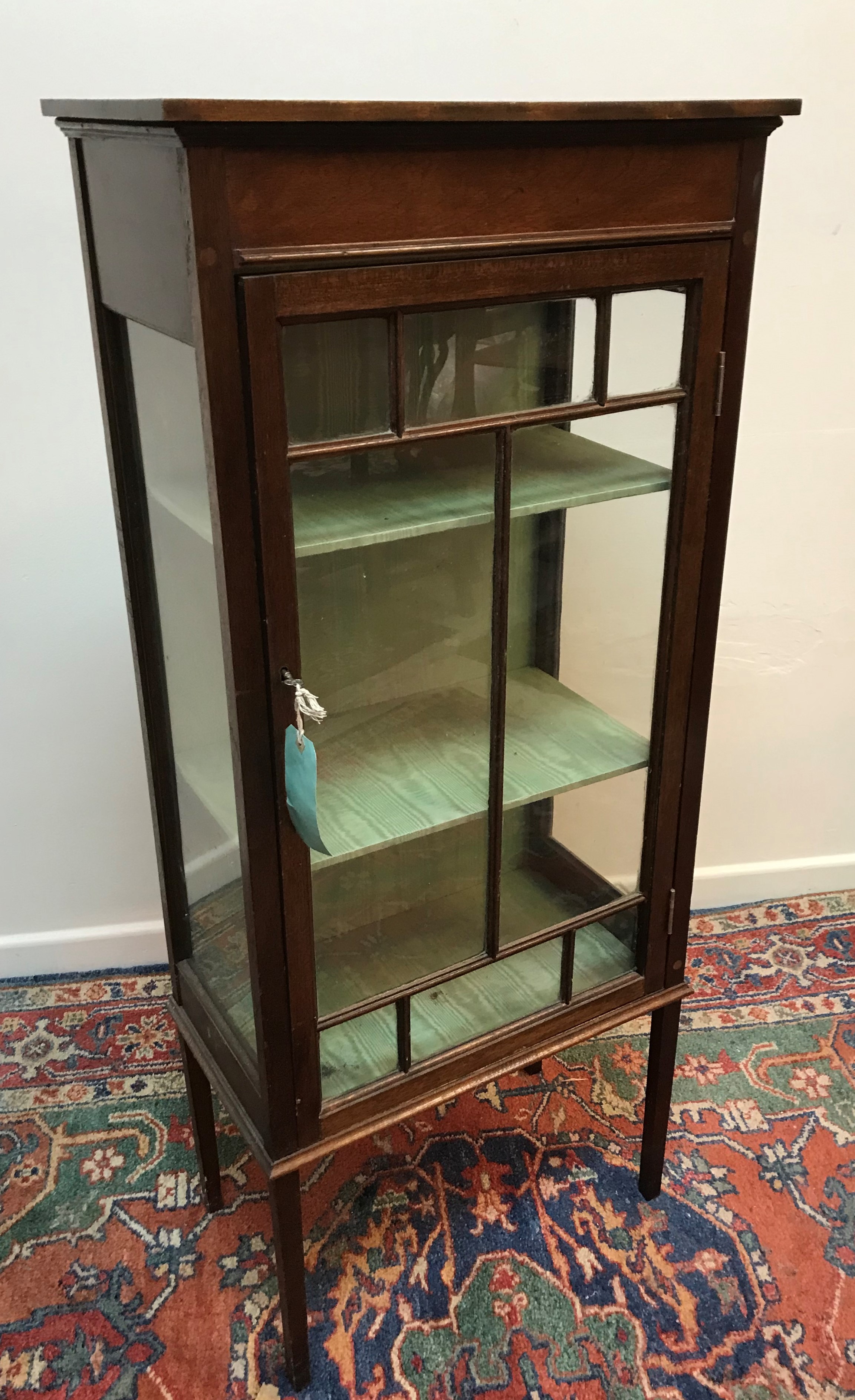 An Edwardian mahogany display cabinet with simulated marquetry inlaid decorated frieze over a