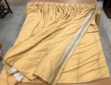 A pair of yellow cotton interlined curtains with braided edging and with taped triple pencil pleat