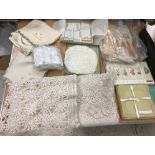 Two boxes of assorted table linens to include crocheted doilies, serviettes, tray cloths, etc,