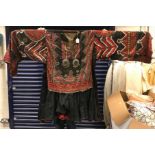 A Turkish ethnic top with button, coin and embroidered decoration on a black ground,