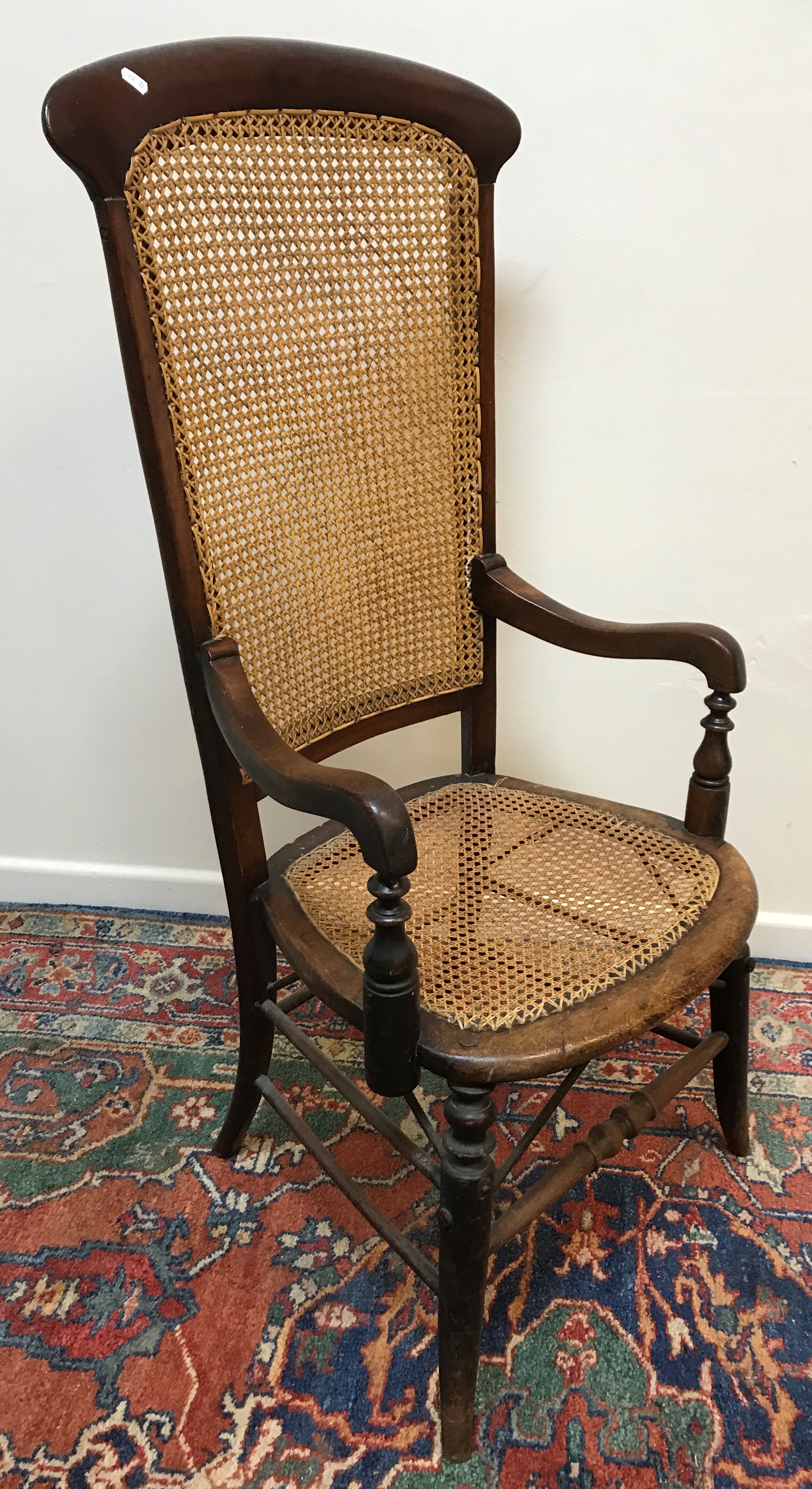 A Victorian cane back and seated mahogany framed elbow chair on turned legs united by stretchers 56