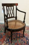 An early 19th Century black lacquered and chinoiserie decorated cane seated elbow chair on turned