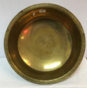 An early 20th Century beaten brass circular pan with crescent decorated rim,