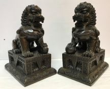 A pair of 19th Century Chinese chocolate patinated bronze figures of temple lions with foot upon a