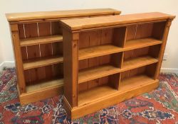 A pair of modern stained pine open bookcases of two banks of three shelves, raised on plinth bases,