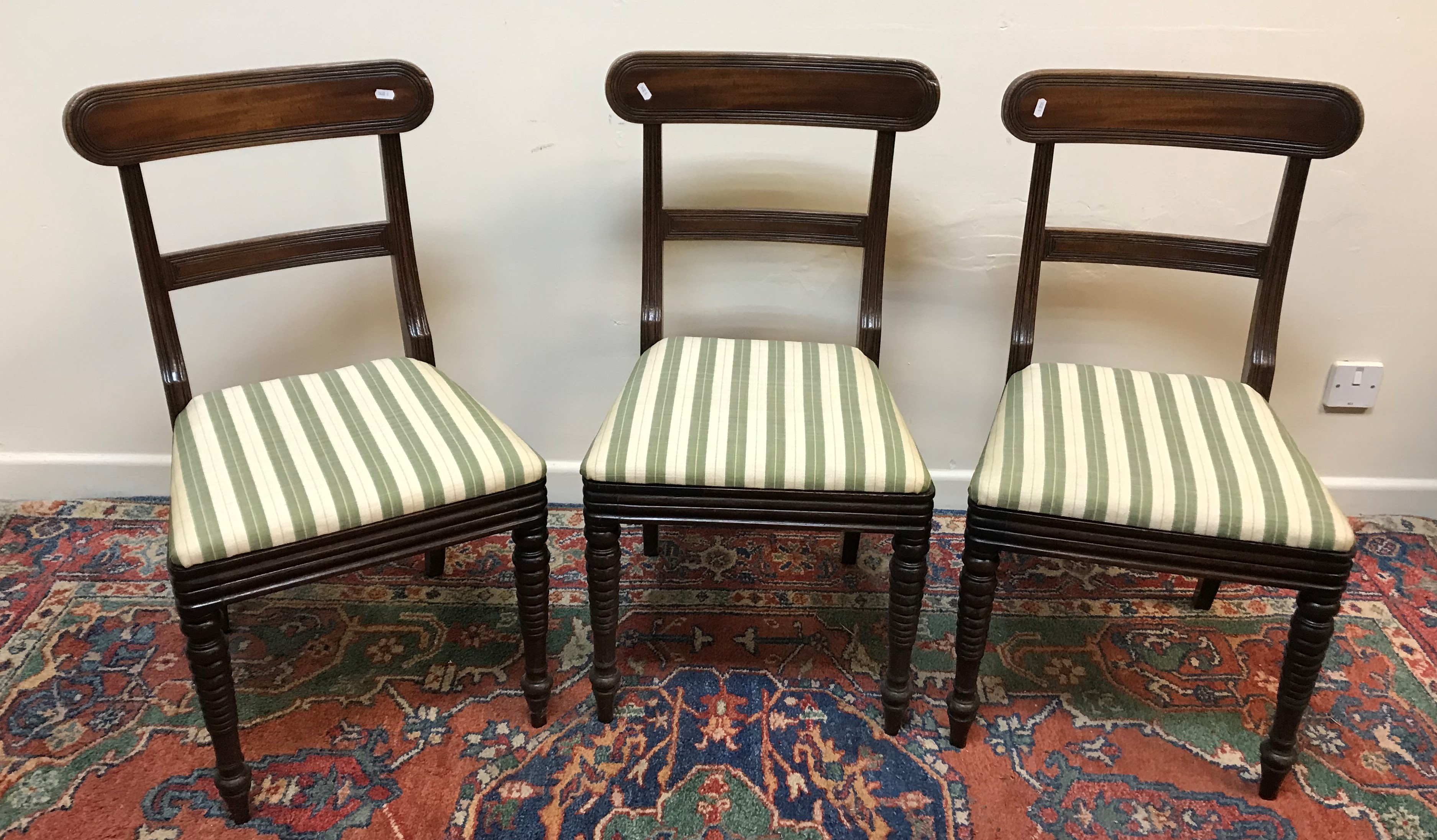 A set of three Regency mahogany bar back dining chairs with upholstered seats on turned front legs,