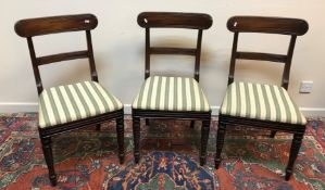 A set of three Regency mahogany bar back dining chairs with upholstered seats on turned front legs,