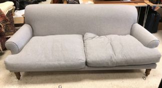 A modern pale grey upholstered scroll arm sofa on turned and stained beech front legs 228 cm wide x