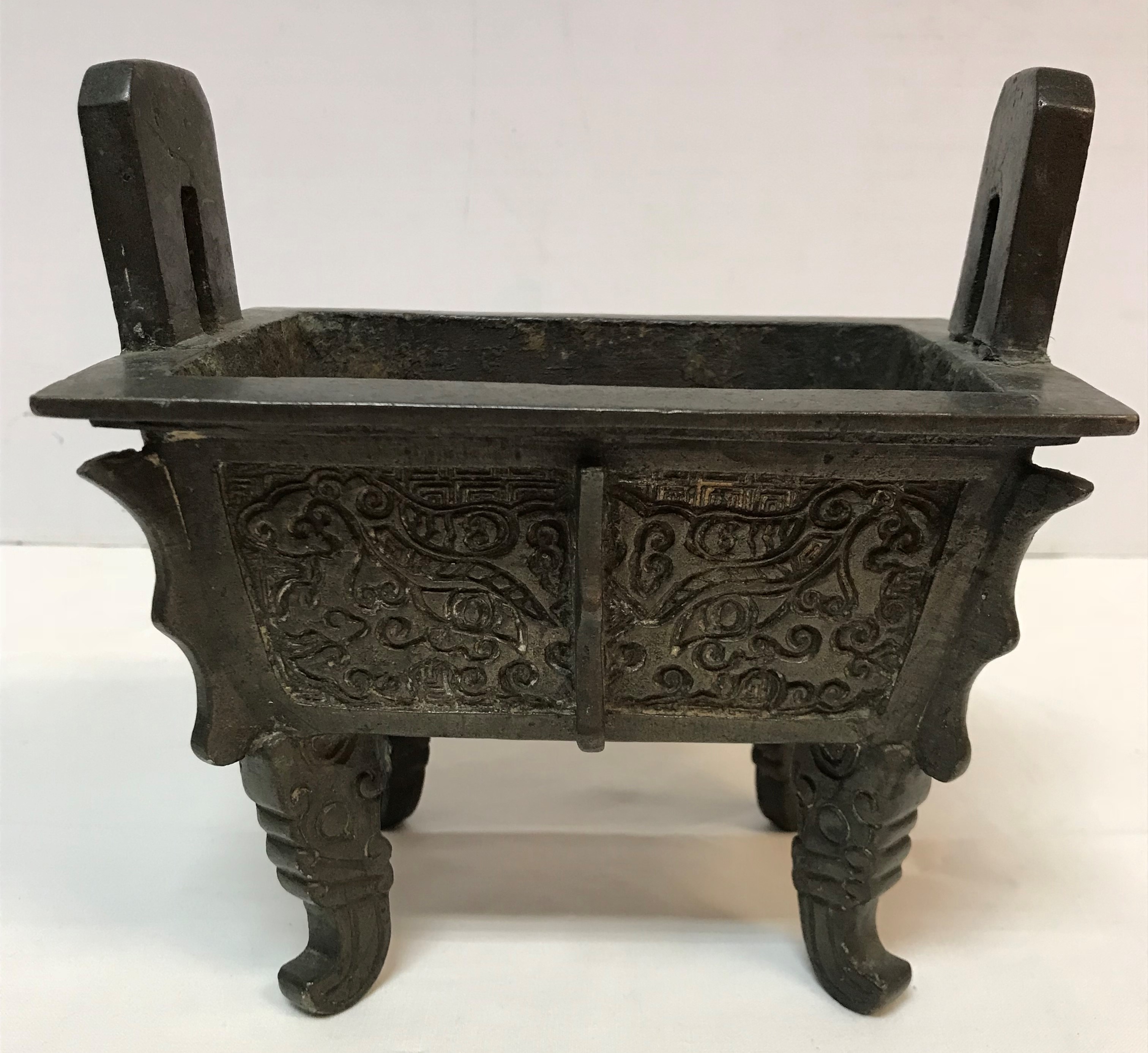 A Chinese bronze censer of rectangular form with relief work foliate decoration,